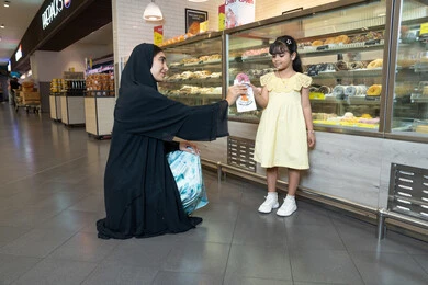 Emirati Woman Buying Donuts for Young Girl in Bakery
