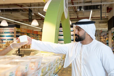 Emirati Man Receiving Food Sample at Supermarket Counter