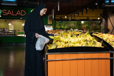 Emirati Woman Shopping for Fresh Bananas in Supermarket