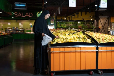 امرأة إماراتية تتسوق الفواكه الطازجة في السوبر ماركت