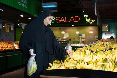 Emirati Woman Shopping for Fresh Bananas in Supermarket