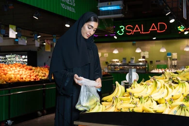 Emirati Woman Shopping for Fresh Bananas in Supermarket