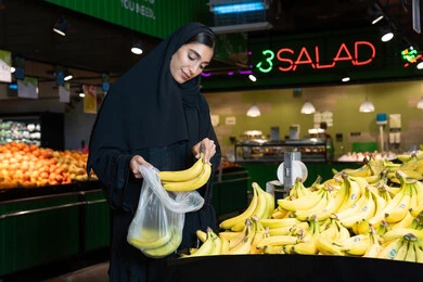 Emirati Woman Shopping for Fresh Bananas in Supermarket