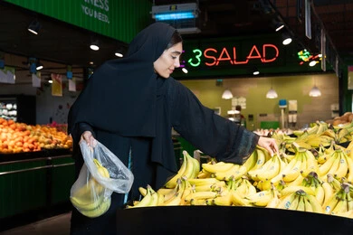 امرأة إماراتية تشتري الموز الطازج من السوبر ماركت