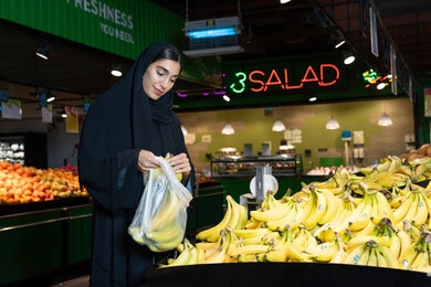 امرأة إماراتية تشتري الفواكه الطازجة من السوبر ماركت