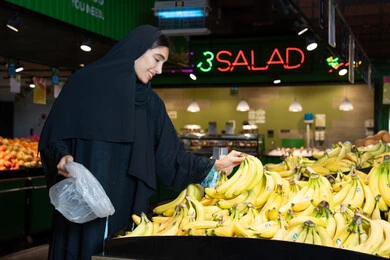 Emirati Woman Shopping for Fresh Bananas in Supermarket
