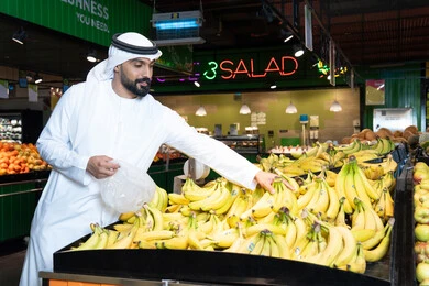 Emirati Man Shopping for Fresh Bananas in Supermarket