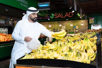 Emirati Man Shopping for Fresh Bananas in Supermarket