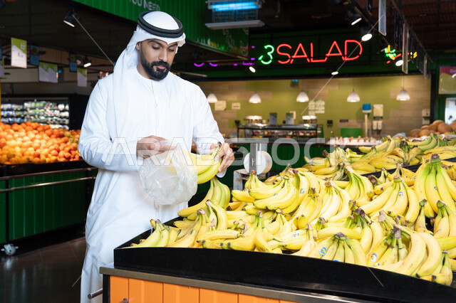 Emirati Man Shopping for Fresh Bananas in Supermarket