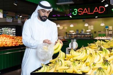 Emirati Man Shopping for Fresh Bananas in UAE Supermarket