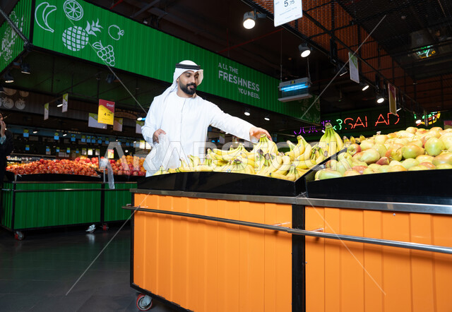 رجل إماراتي يتسوق الفاكهة الطازجة في السوبر ماركت