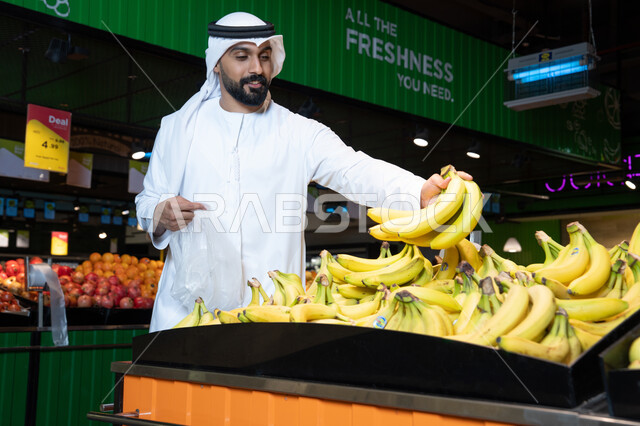 رجل إماراتي يتسوق الموز الطازج في السوبر ماركت