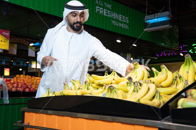 تسوق رجل إماراتي للموز الطازج في قسم الفواكه بالسوبر ماركت