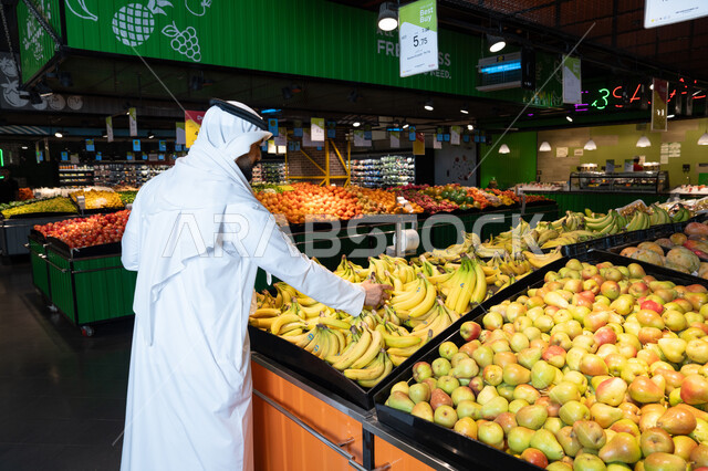 رجل إماراتي يتسوق الفاكهة الطازجة في السوبر ماركت