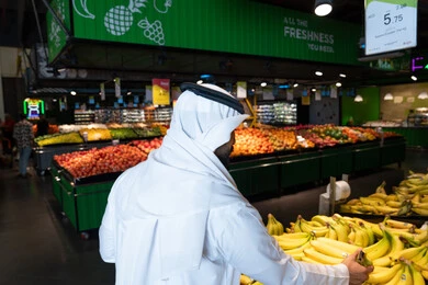 رجل إماراتي يتسوق الفواكه الطازجة في السوبر ماركت