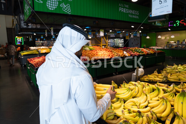رجل إماراتي يتسوق الفاكهة الطازجة في السوبر ماركت