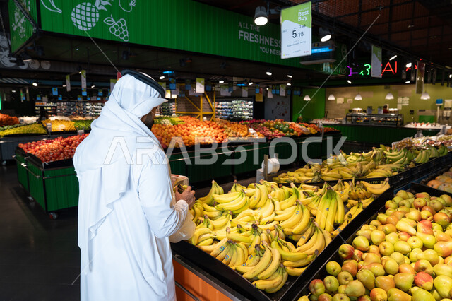 رجل إماراتي يتسوق الفواكه الطازجة في السوبر ماركت