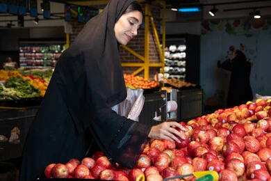 Emirati Woman Shopping for Red Apples in UAE Supermarket