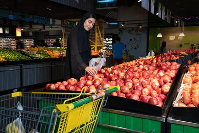 Emirati Woman Shopping for Fresh Apples in Supermarket