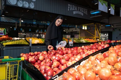 Emirati Woman Shopping for Fresh Red Apples in Supermarket