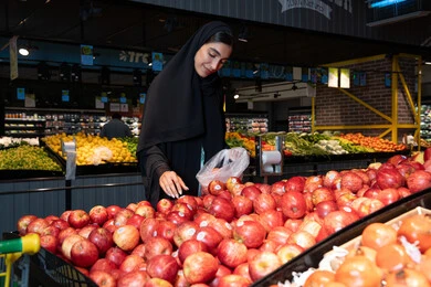 Emirati Woman Shopping for Red Apples in UAE Supermarket