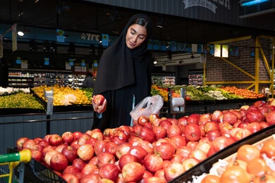 Emirati Woman Shopping for Fresh Red Apples in Supermarket