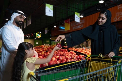 عائلة إماراتية تتسوق التفاح الطازج في مركز تجاري