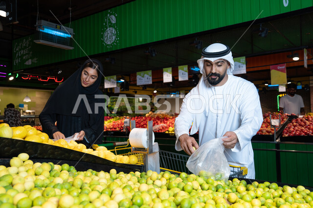 زوجان إماراتيان يتسوقان الفاكهة الطازجة في السوبر ماركت