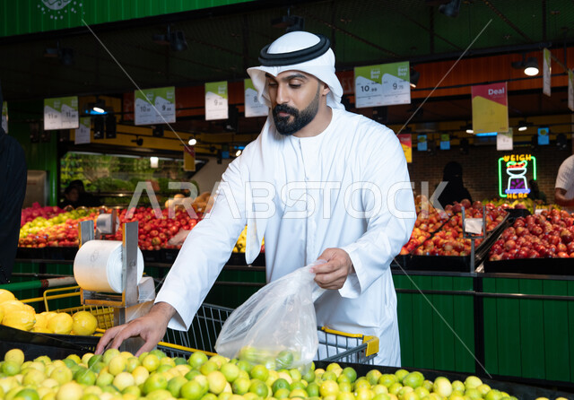 رجل إماراتي في السوبر ماركت يختار الليمون الأصفر الطازج