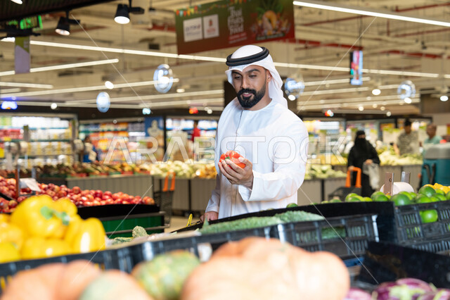 رجل إماراتي يتسوق الخضروات الطازجة في السوبر ماركت