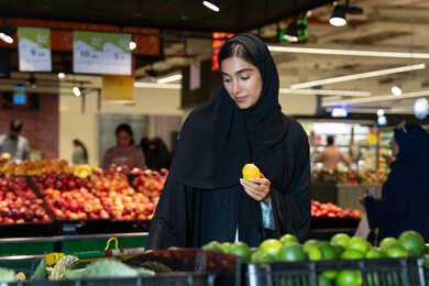 امرأة إماراتية تتسوق الخضروات والفواكه في السوبر ماركت