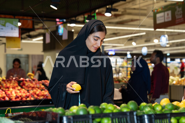 امرأة إماراتية تتسوق الفواكه الطازجة في السوبر ماركت