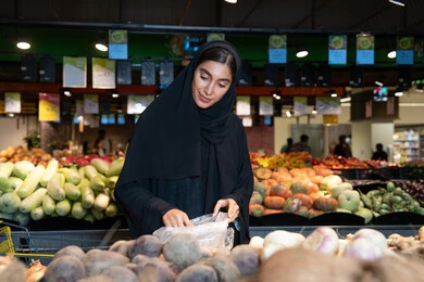 امرأة إماراتية تتسوق الخضروات الطازجة في السوبر ماركت