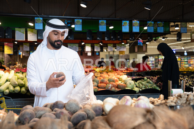 رجل إماراتي يختار الخضروات الطازجة في السوبر ماركت