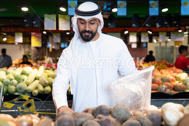 رجل إماراتي يتسوق الخضروات الطازجة في السوبر ماركت