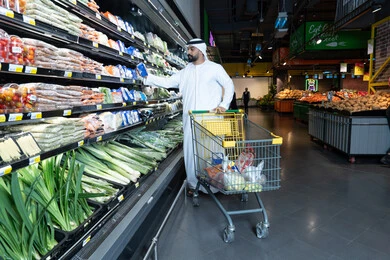 رجل إماراتي يتسوق الخضروات في سوبر ماركت حديث