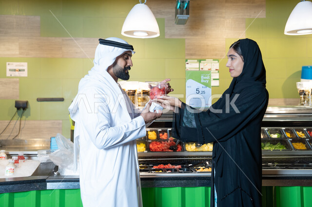 زوجان إماراتيان يتسوقان الفواكه الطازجة في سوبر ماركت