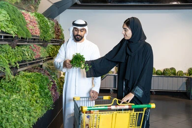 زوجين إماراتيين يتسوقون الخضروات الطازجة في السوبر ماركت
