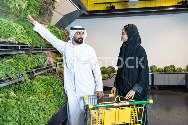 رجل وامرأة إماراتيان يتسوقان الخضروات في السوبر ماركت