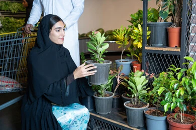 سيدة إماراتية تختار نباتات الزينة في مشتل المتجر