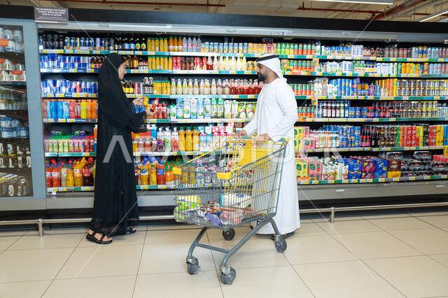 زوجان إماراتيان يتسوقان في ممر سوبر ماركت حديث