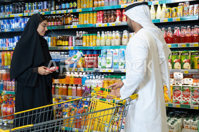 زوجين إماراتيين يتسوقان في قسم المشروبات بالسوبر ماركت