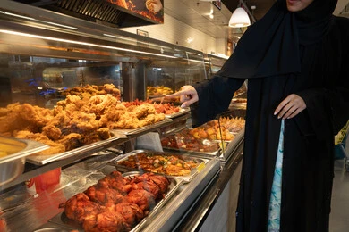 Emirati Woman in Supermarket Deli Food Section