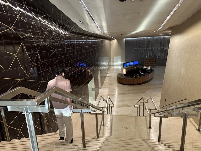 رجل يستخدم درج مركز اثراء، 5 أكتوبر 2025، مكان للقراء ومحبي العلم والكتب والمعرفة، أكبر المكتبات العامة في السعوديه، مركز الملك عبد العزيز الثقافي العالمي (إثراء) في مدينة الظهران في المملكة العربية السعودية, كتب و روايات وقصص مرتبة في الرفوف.