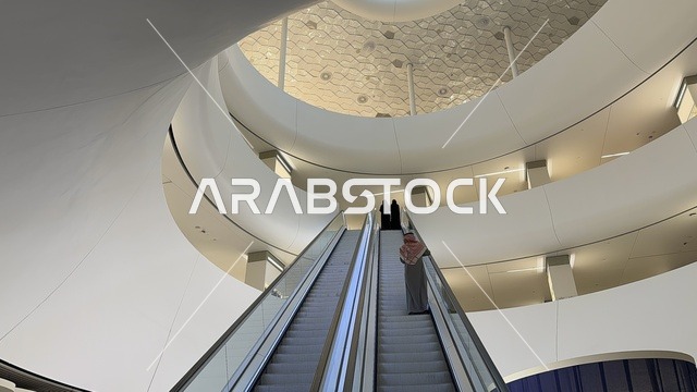 An interior image of a woman ascending the stairs of the Ithra Center, October 5, 2025, a place for readers and lovers of knowledge, books, and learning, the largest public library in Saudi Arabia, the King Abdulaziz Center for World Culture (Ithra) in Dhahran, Saudi Arabia, with books, novels, and stories arranged on the shelves.