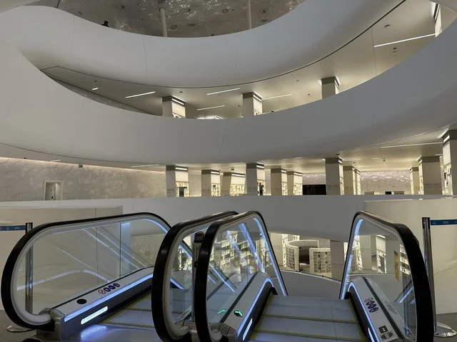 سلم متحرك للتنقل بين الادوار، 5 أكتوبر 2025، مكان للقراء ومحبي العلم والكتب والمعرفة، أكبر المكتبات العامة في السعوديه، مركز الملك عبد العزيز الثقافي العالمي (إثراء) في مدينة الظهران في المملكة العربية السعودية, كتب و روايات وقصص مرتبة في الرفوف.