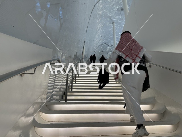 زوار المكتبة يصعدون سلم في المكان، 5 أكتوبر 2025، مكان للقراء ومحبي العلم والكتب والمعرفة، أكبر المكتبات العامة في السعوديه، مركز الملك عبد العزيز الثقافي العالمي (إثراء) في مدينة الظهران في المملكة العربية السعودية, كتب و روايات وقصص مرتبة في الرفوف.