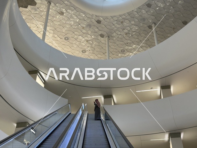 An interior image of a woman ascending the stairs of the Ithra Center, October 5, 2025, a place for readers and lovers of knowledge, books, and learning, the largest public library in Saudi Arabia, the King Abdulaziz Center for World Culture (Ithra) in Dhahran, Saudi Arabia, with books, novels, and stories arranged on the shelves.