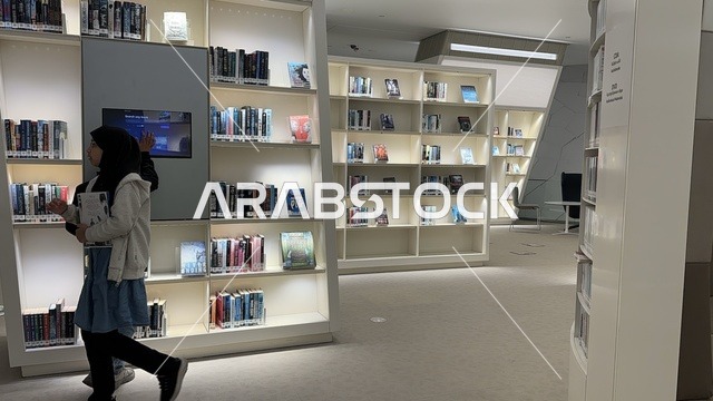 طفلين يقومان بتصفح الكتب في مكتبة،منارة ثقافية و معالم سياحية مشهورة, مكان للقراء ومحبي العلم والكتب والمعرفة، أكبر المكتبات العامة في السعوديه،  5 أكتوبر 2025، مركز الملك عبد العزيز الثقافي العالمي (إثراء) في مدينة الظهران في المملكة العربية السعودية.