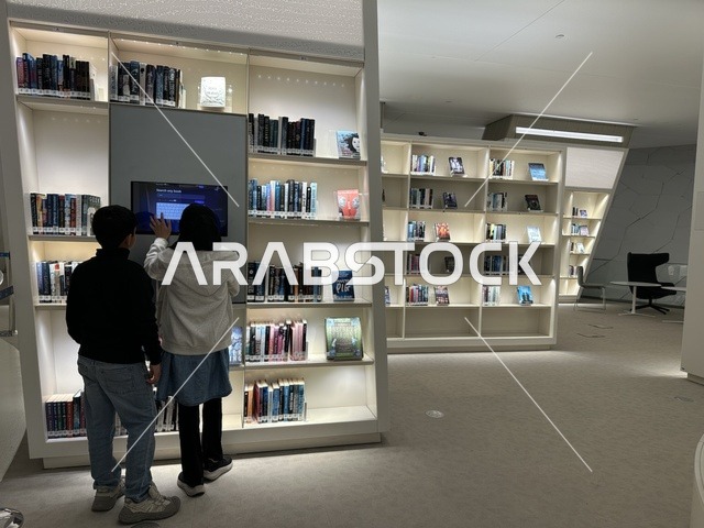 طفلين يقومان بتصفح الكتب في مكتبة،منارة ثقافية و معالم سياحية مشهورة, مكان للقراء ومحبي العلم والكتب والمعرفة، أكبر المكتبات العامة في السعوديه،  5 أكتوبر 2025، مركز الملك عبد العزيز الثقافي العالمي (إثراء) في مدينة الظهران في المملكة العربية السعودية.